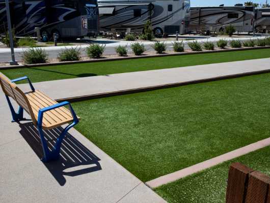 park bench next to artificial grass bocce court